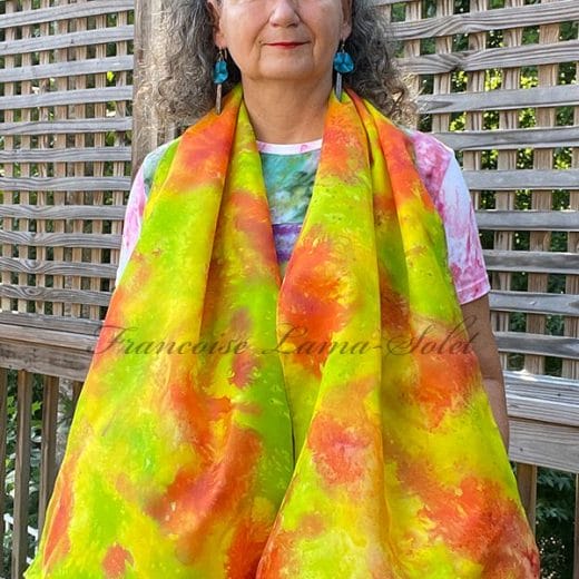 Women's silk scarf hand painted with an abstract print in different shades of green, yellow and orange.