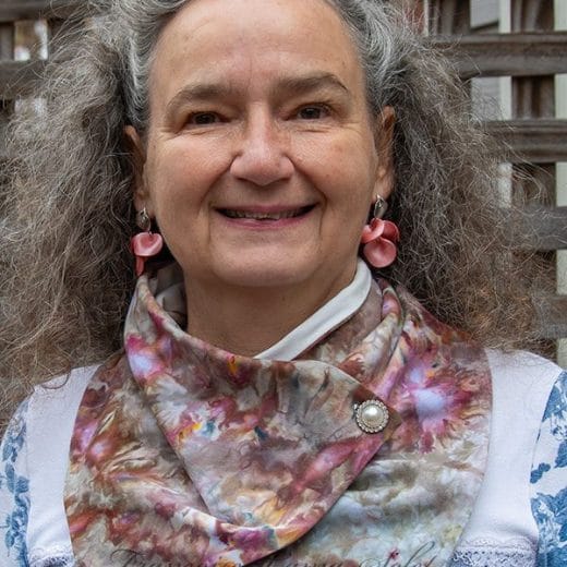 Hand-dyed neck warmer scarf with unique ice-dye patterns in shades of coral, maroon, grey, brown, and olive green, made from soft cotton lycra jersey and featuring a button closure.
