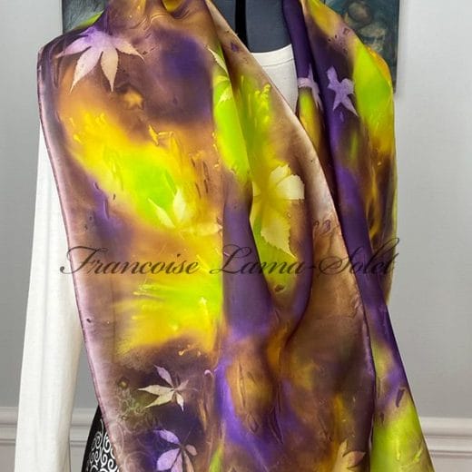 Hand-painted silk scarf in vibrant purple, chartreuse green, and brown shades, featuring natural leaf impressions created using sun printing.