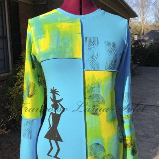 A vibrant long-sleeve t-shirt made of soft cotton lycra jersey, featuring hand-painted abstract patterns in yellow, green, and turquoise blue, accented with bold black tribal-inspired prints and visible seams for a modern look.
