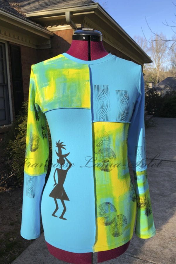 A vibrant long-sleeve t-shirt made of soft cotton lycra jersey, featuring hand-painted abstract patterns in yellow, green, and turquoise blue, accented with bold black tribal-inspired prints and visible seams for a modern look.