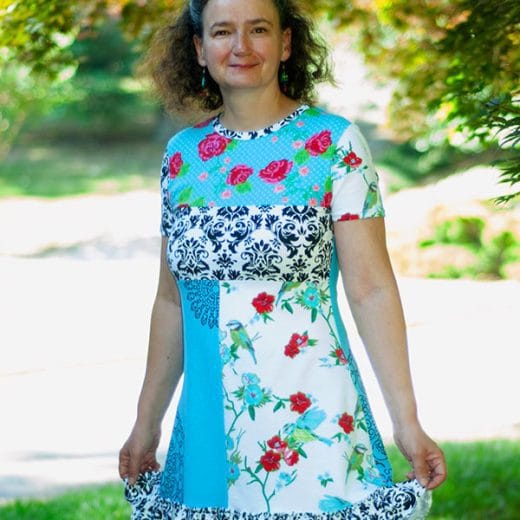 Vibrant short-sleeve A-line tunic, handmade with a mix of solid turquoise and floral jersey fabrics, featuring unique hand-printed doily patterns for a one-of-a-kind artistic touch