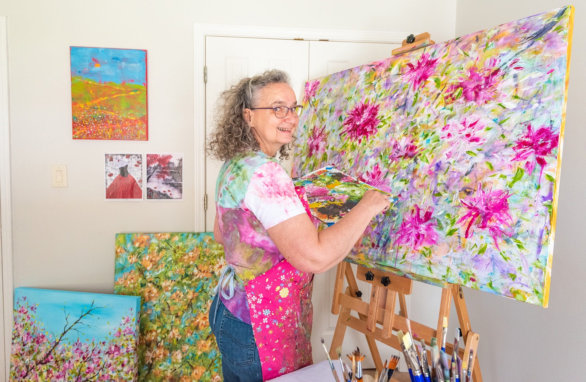 Françoise Lama-Solet painting indoors, carefully working on her canvas with focused brushstrokes, bringing her artistic vision to life