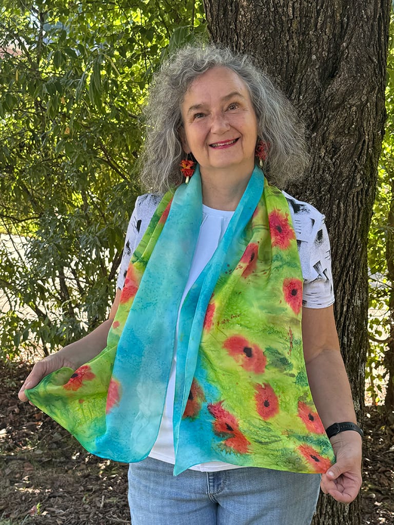 Vibrant hand painted silk scarf featuring red poppies in a field